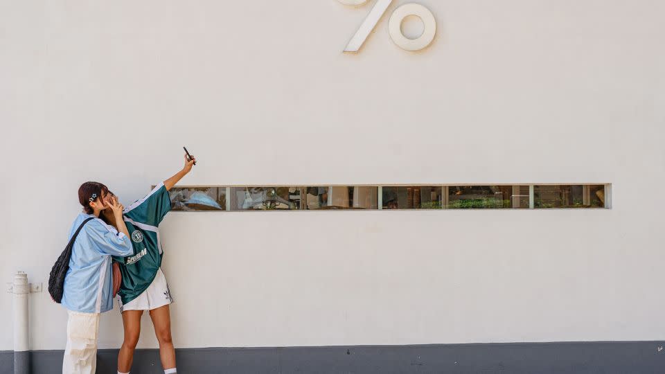 Girls take pictures in front of a Kennedy Town district cafe in Hong Kong. - Noemi Cassanelli/CNN