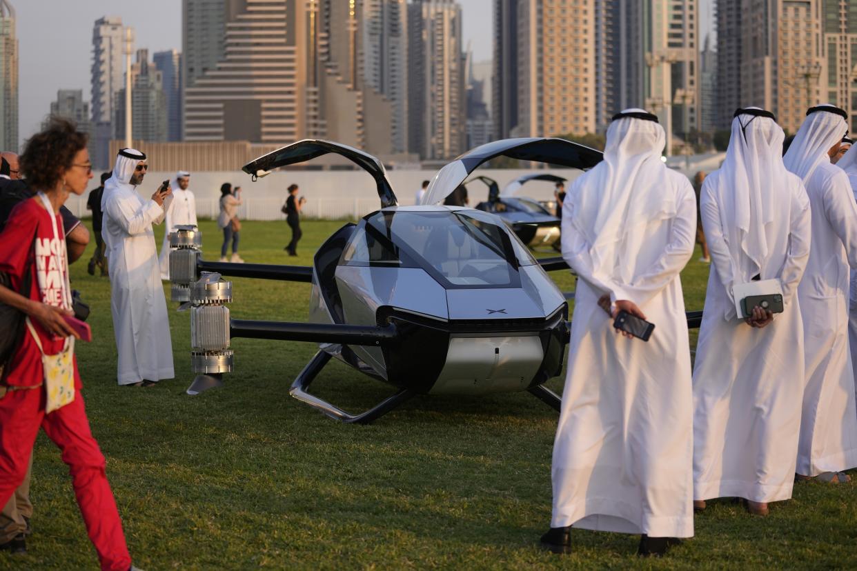 People look at the XPeng X2, an electric flying taxi developed by the Guangzhou-based XPeng, Inc's aviation affiliate, being tested in front of the Marina District in Dubai, United Arab Emirates, Monday, Oct. 10, 2022. Monday’s demonstration was held with an empty cockpit, but the company says it carried out a manned flight test last year of the two-passenger vehicle. (AP Photo/Kamran Jebreili)