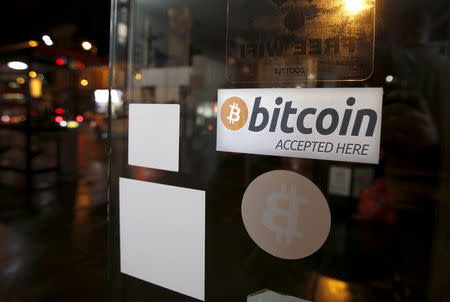 A bitcoin sticker is seen in the window of the 'Vape Lab' cafe, where it is possible to both use and purchase the bitcoin currency, in London March 24, 2015. REUTERS/Peter Nicholls