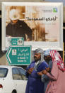 Workers wait in front of a billboard displaying an advertisement for Saudi Arabia's state-owned oil giant Aramco with Arabic reading: "Saudi Aramco, soon on stock exchange" in Jiddah, Saudi Arabia, Tuesday, Nov. 12, 2019. Saudi Aramco is the kingdom's oil and gas producer, pumping more than 10 million barrels of crude oil a day, or some 10% of global demand. (AP Photo/Amr Nabil)