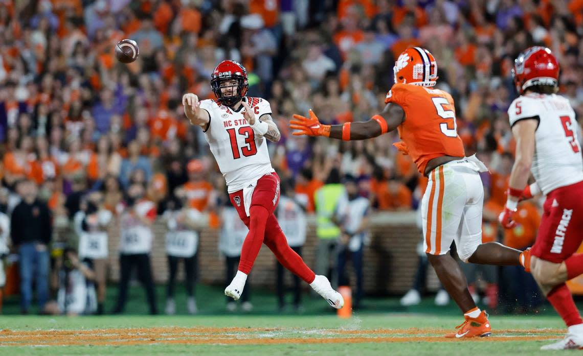 N.C. State quarterback Devin Leary (13) throws the ball to wide receiver Thayer Thomas (5) as Clemson defensive end K.J. Henry (5) defends during the first half of N.C. State’s game against Clemson at Memorial Stadium in Clemson, S.C., Saturday, Oct. 1, 2022.