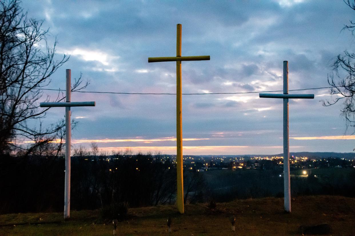 The sun rises behind three crosses at the east end of the Living Word Outdoor Drama parking lot as Cambridge glows in the distance.