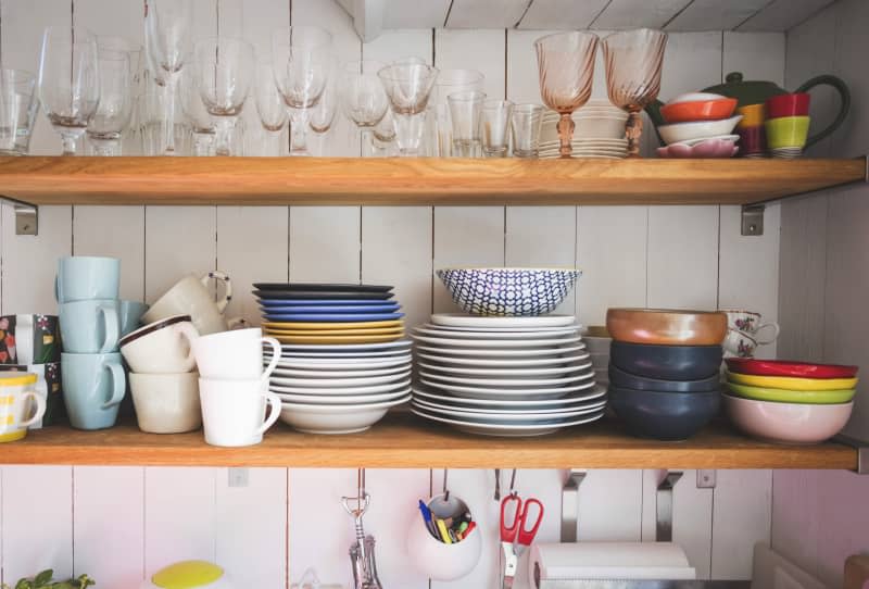 Crockery and drinking glasses on shelves in kitchen at home