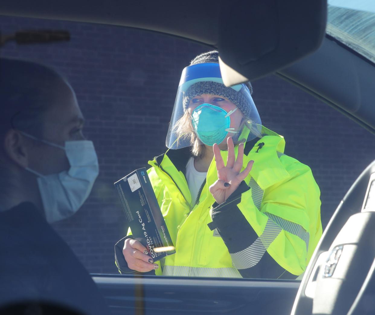 Summit County public health worker Marlene Martin asks a driver how many passengers are in her vehicle before handing out free coronavirus testing kits Jan. 8 in Akron, Ohio.