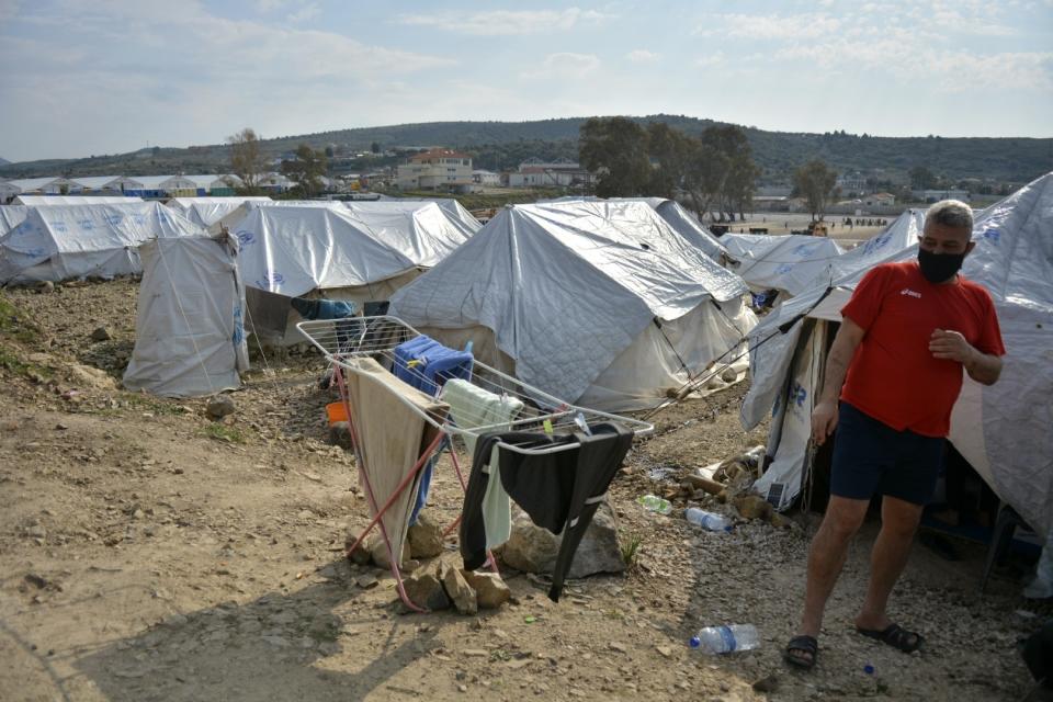 A migrant stands outside his tent at Karatepe refugee camp, on the northeastern Aegean island of Lesbos, Greece, Monday, March 29, 2021. The European Union's home affairs commissioner is visiting asylum-seeker facilities on the eastern Greek islands of Samos and Lesbos amid continuing accusations against Greece of illegal summary deportations. (AP Photo/Panagiotis Balaskas)