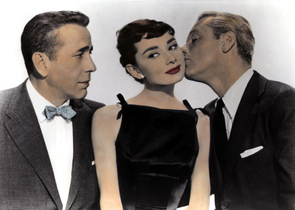 Humphrey looking on as William kisses Audrey's cheek, all three in formal wear