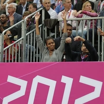 First Lady Michelle Obama participates in the wave during the first half of a preliminary men's basketball game between the USA and France at the 2012 Summer Olympics, Sunday, July 29, 2012, in London. (AP Photo/Charles Krupa)