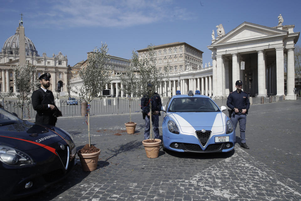 Small olive trees are placed next to the patrol of Italian police in St. Peter's Square at the Vatican as Pope Francis celebrates Palm Sunday Mass behind closed doors at the Vatican, Sunday, April 5, 2020, during the lockdown aimed at curbing the spread of the COVID-19 infection, caused by the novel coronavirus. The new coronavirus causes mild or moderate symptoms for most people, but for some, especially older adults and people with existing health problems, it can cause more severe illness or death. (AP Photo/Alessandra Tarantino)