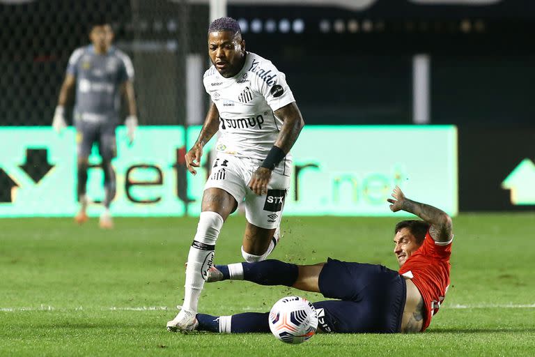 Lucas Rodríguez (derecha) y el brasileño Santos Marinho compiten por el balón durante el partido de ida de los octavos de final de la Copa Sudamericana en el estadio Urbano Caldeira de Santos, Brasil, el 15 de julio de 2021