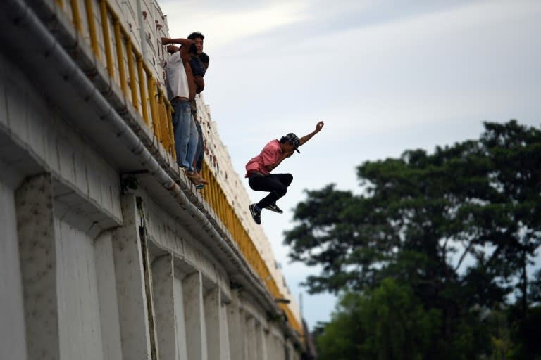 A Honduran migrant jumps to the Suchiate River from the Guatemala-Mexico international border bridge to swim and reach Mexico