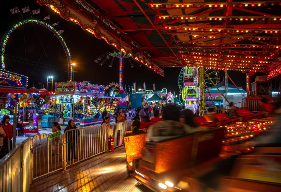 Fairgoers spin around on a racecar-themed ride during the Riverside County Fair & National Date Festival in Indio, Calif., Tuesday, Feb. 21, 2023. 