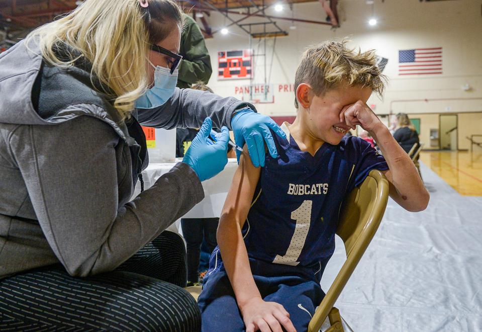 Eli Bryant, age 8, can't bare to watch as he receives his flu and COVID vaccines from nurse Amanda Dement at the Alluvion Health vaccine clinic on Wednesday evening at Paris Gibson Education Center.