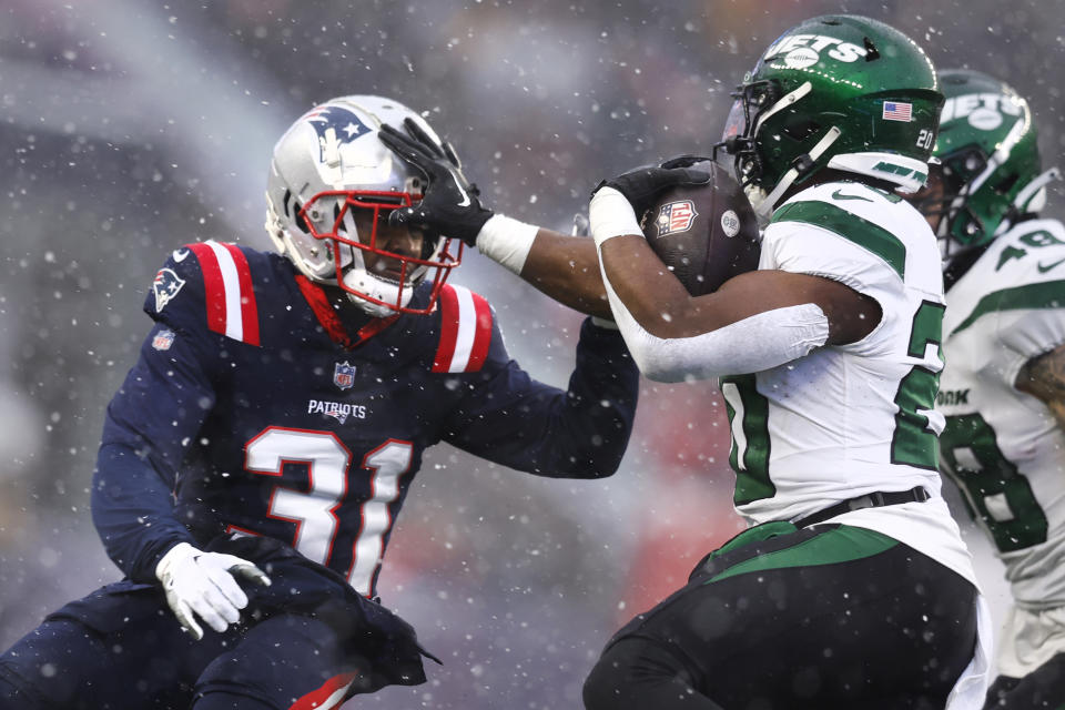 New York Jets running back Breece Hall, right, pushes New England Patriots cornerback Jonathan Jones (31) on his run during the first half of an NFL football game, Sunday, Jan. 7, 2024, in Foxborough, Mass. (AP Photo/Michael Dwyer)