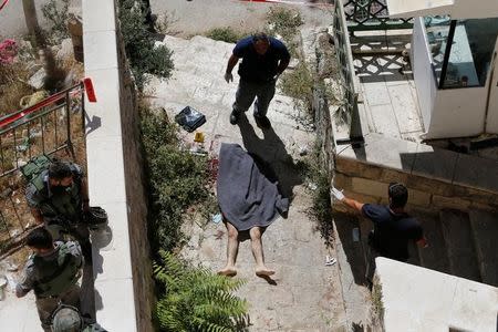 Israeli security forces gather near the body of a Palestinian assailant who was shot dead by Israeli troops, at the scene of a stabbing attack in the West Bank city of Hebron September 19, 2016. REUTERS/Mussa Qawasma