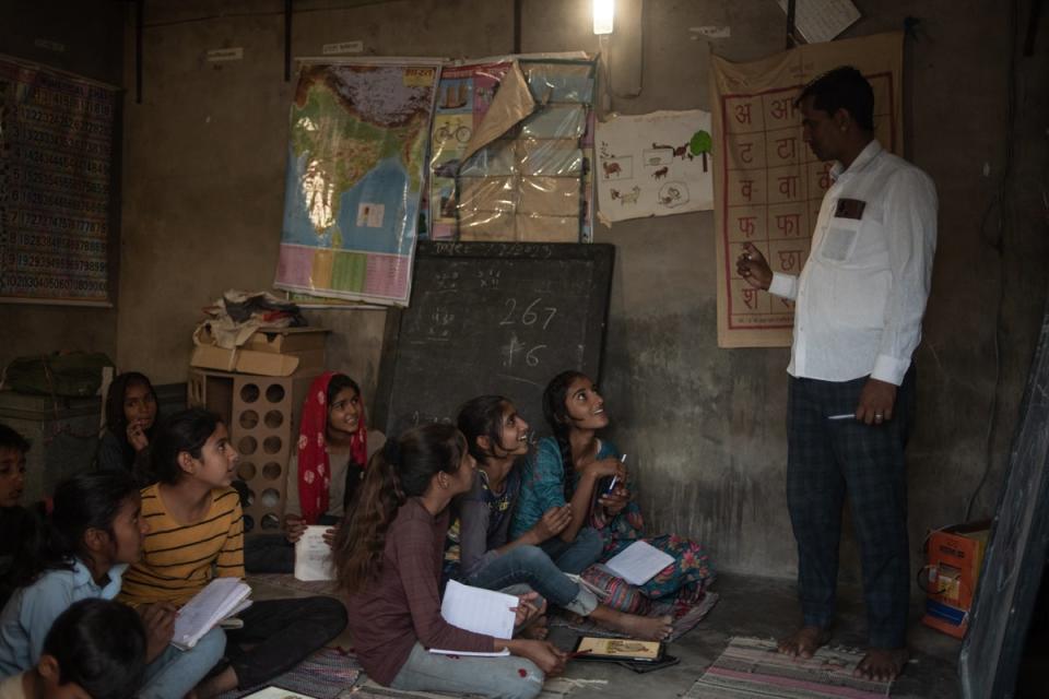 Indian school children attend a lesson at a ‘night school’, which runs in the evenings using light generated by solar power and enables children to study longer and catch up on lessons on 25 March (Getty)
