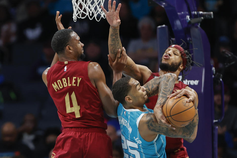 Charlotte Hornets forward P.J. Washington pulls down a rebound against Cleveland Cavaliers forwards Lamar Stevens (8) and Evan Mobley during the first half of an NBA basketball game in Charlotte, N.C., Sunday, March 12, 2023. (AP Photo/Nell Redmond)