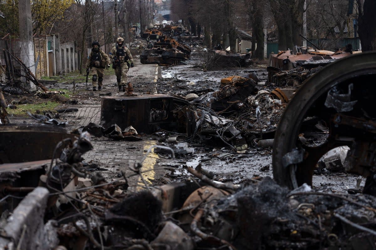 Soldiers walk amid destroyed Russian tanks in the outskirts of Kyiv (AP)