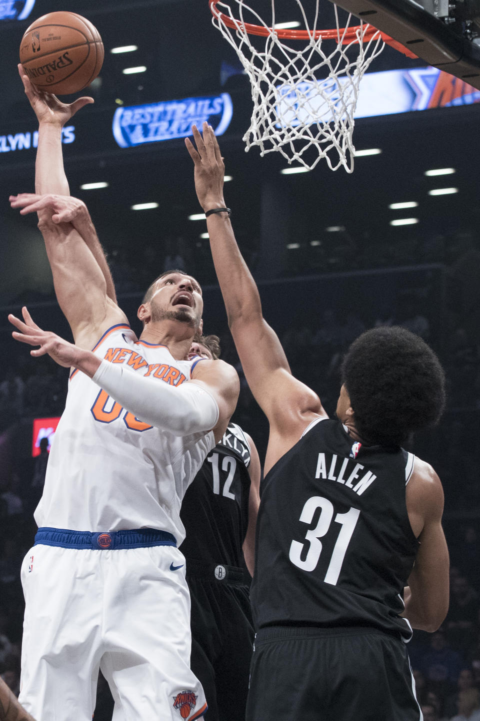 New York Knicks center Enes Kanter (00) goes to the basket against Brooklyn Nets center Jarrett Allen (31) and forward Joe Harris (12) during the first half of an NBA basketball game, Friday, Oct. 19, 2018, in New York. (AP Photo/Mary Altaffer)