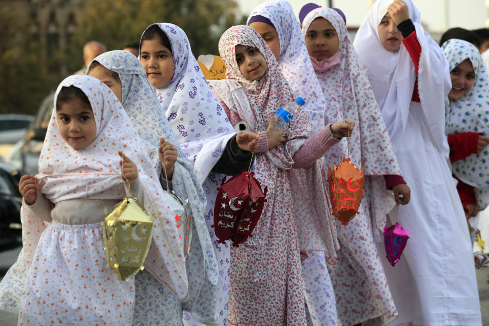 Lebanese girls hold traditional lanterns, during street performances celebrating the upcoming Muslim holy month of Ramadan, in the southern port city of Sidon, Lebanon, Thursday, March 31, 2022. (AP Photo/Mohammed Zaatari)