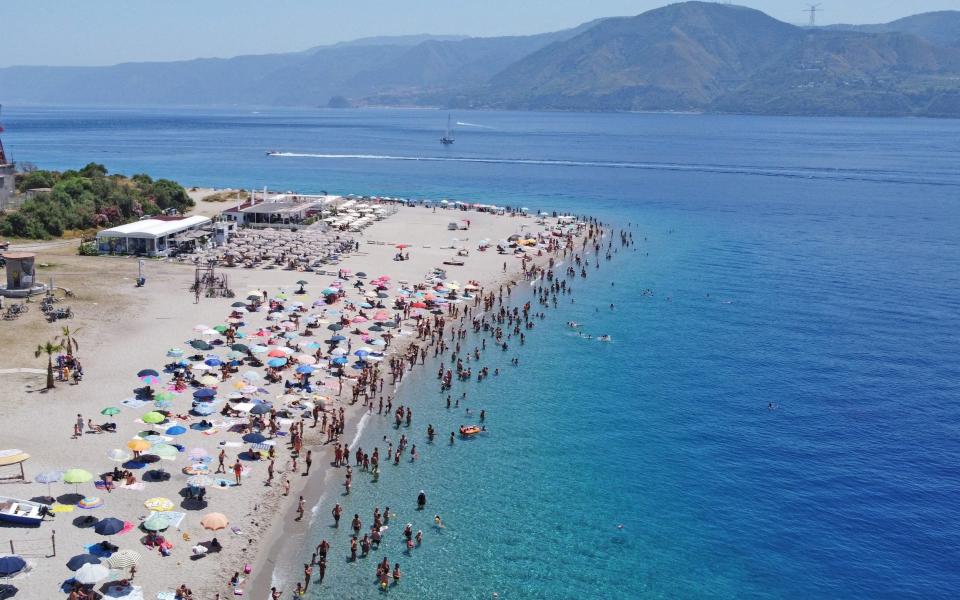 Tourists chilling out along Torre Faro Pilone beach on the island of Sicily