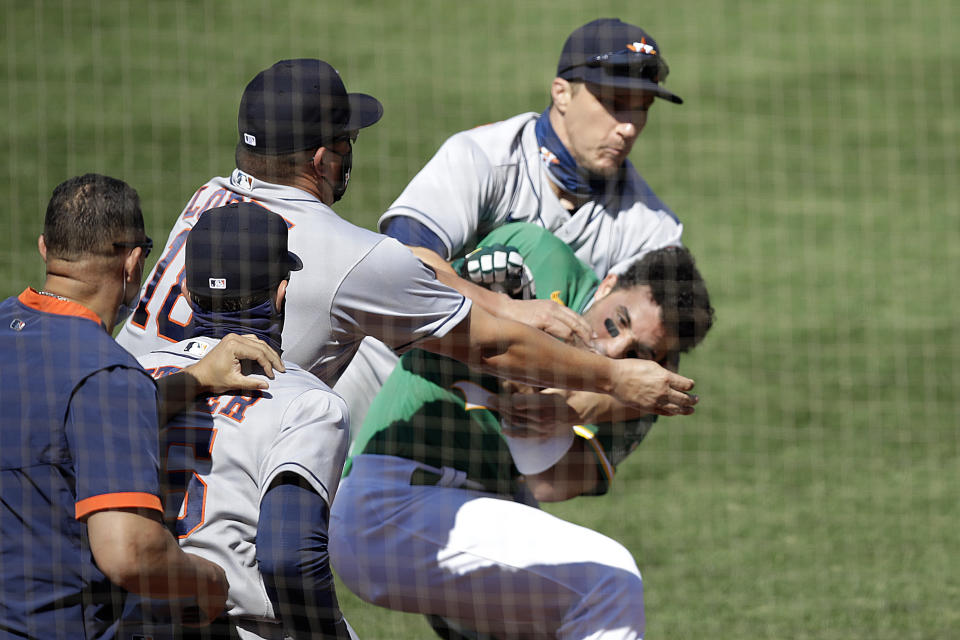 Oakland Athletics' Ramon Laureano is restrained by Houston Astro's Dustin Garneau after Laureano charged the dugout after being hit by a pitch thrown by Humberto Castellanos in the seventh inning of a baseball game Sunday, Aug. 9, 2020, in Oakland, Calif. (AP Photo/Ben Margot)