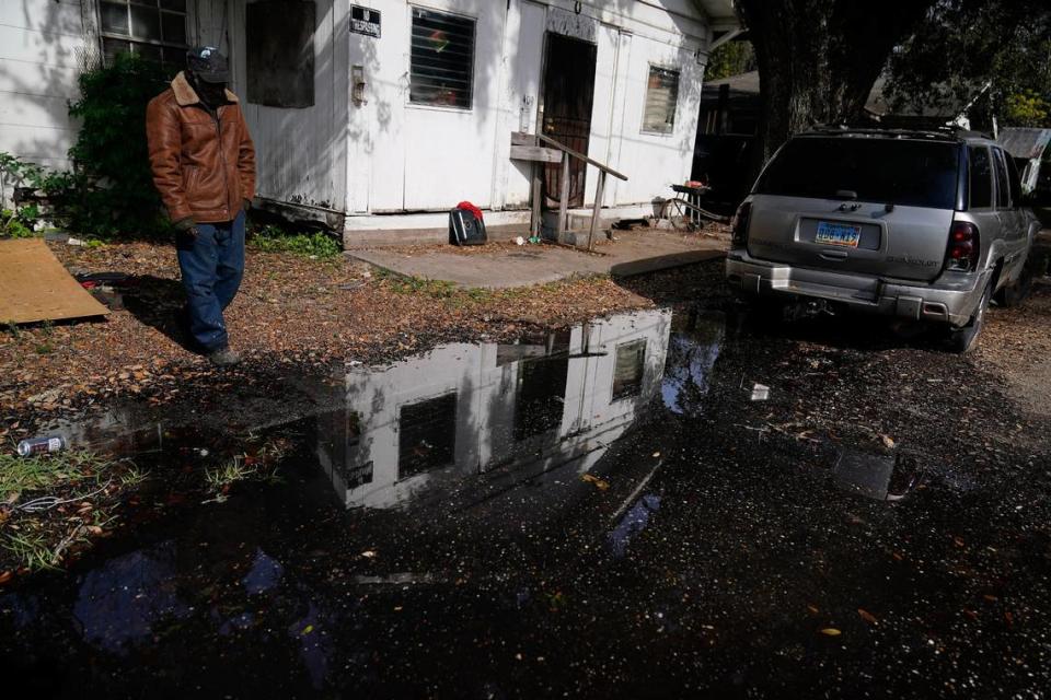 A man stands near his home looking at a street he says has been flooded for months in Prichard, Ala.