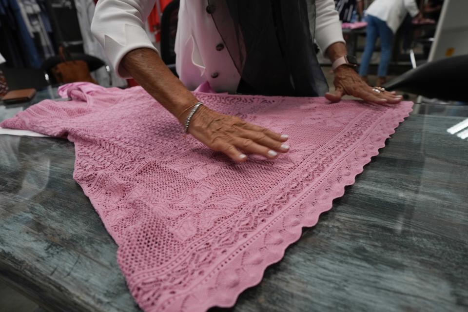 Nadia Zanola, chairman of the Cose di Maglia factory and owner of the D.Exterior brand, shows the quality of a dress in Brescia, Italy, Tuesday, June 14, 2022. Small Italian fashion producers are still allowed to export to Russia, despite sanctions, as long as the wholesale price is under 300 euros. But they are having a hard time getting paid, due to restrictions tied to the financial sector. (AP Photo/Luca Bruno)