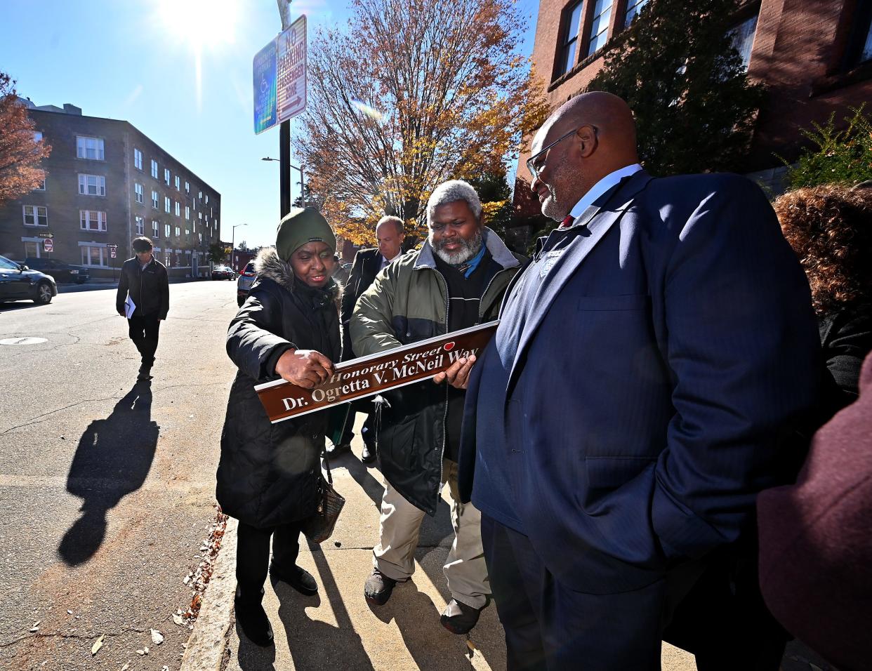 John, right, and Robert Vaughn, sons of Ogretta V. McNeil, with longtime friend Gloria Dhall of Worcester, look over the honorary street sign bearing their mother's name.