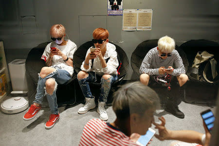 Members of China's all-girl "boyband" FFC-Acrush use their phones before a rehearsal at a dance studio in Beijing April 27, 2017. Picture taken April 27, 2017. REUTERS/Thomas Peter