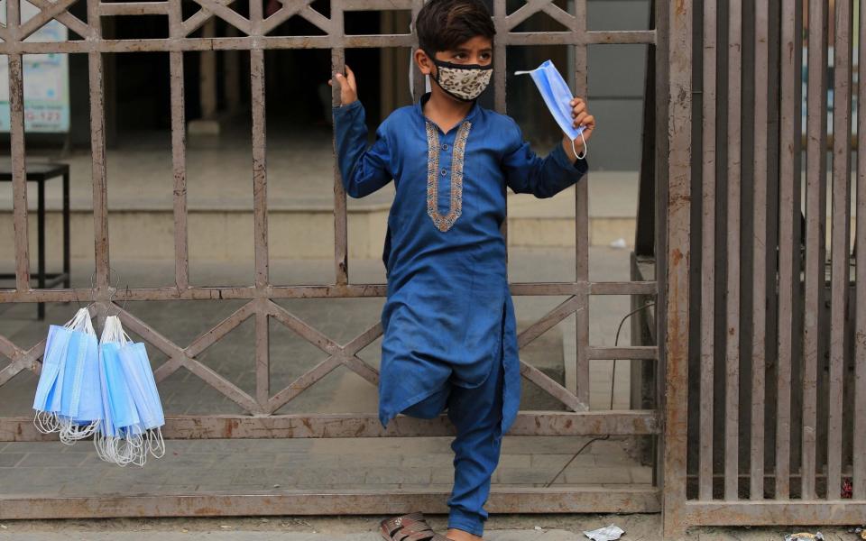 A boy sells protective masks on a road as Pakistan government makes face masks mandatory in public place amid third wave of coronavirus, in Peshawar - ARSHAD ARBAB/EPA-EFE/Shutterstock