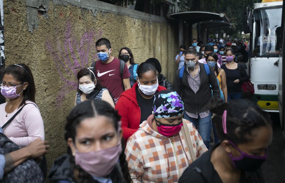 Pedestrians and commuters wearing face masks amid the new coronavirus pandemic crowd a sidewalk near a bus stop in Caracas, Venezuela, Monday, June 1, 2020. After two and a half months of COVID-19 related quarantine, some industries are allowed to reactivate under a scheme of five days' work and 10 days rest. (AP Photo/Ariana Cubillos)