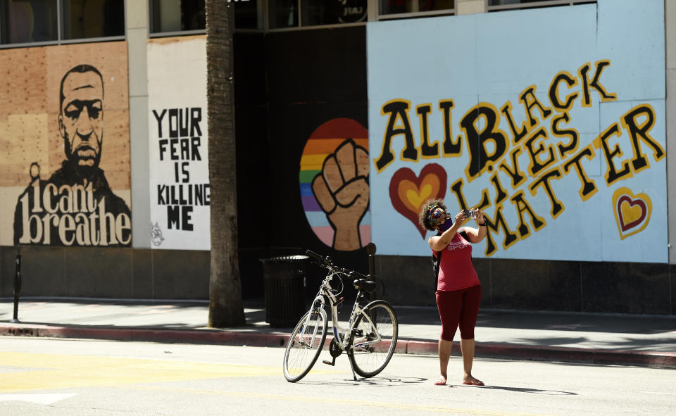 Michelle Artiaga of Los Angeles takes a picture of herself on Hollywood Blvd. a day after a large protest march there, Monday, June 15, 2020, in Los Angeles. Protests continue to be held in U.S. cities over the death of George Floyd, a black man who died after being restrained by Minneapolis police officers on May 25. (AP Photo/Chris Pizzello)