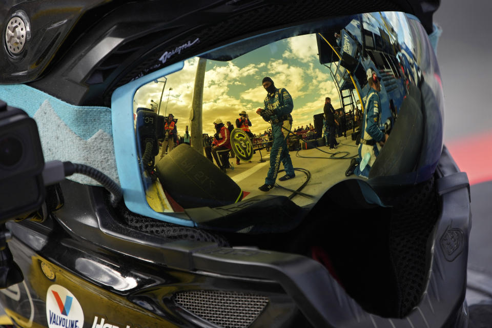 Pit crew members for driver Kyle Larson are reflected in a helmet during a NASCAR Cup Series auto race Sunday, March 6, 2022, in Las Vegas. (AP Photo/John Locher)