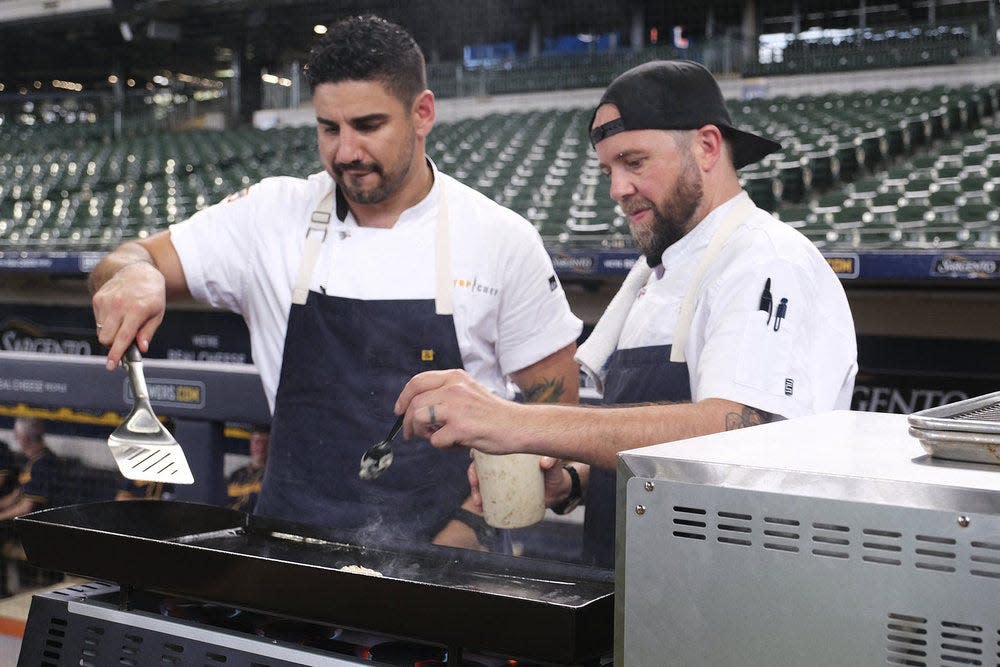 Manny (left) and Dan of the blue team finish preparing their dishes from their on-field cook station at American Family Field during Episode 7 of "Top Chef: Wisconsin."