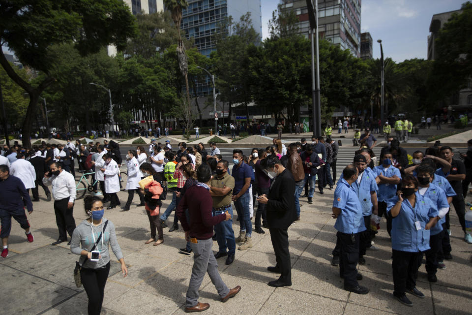 Employees stand outside of their work building after a 7.5 earthquake, in Mexico City, Tuesday, June 23, 2020. The earthquake centered near the resort of Huatulco in southern Mexico swayed buildings Tuesday in Mexico City and sent thousands into the streets.(AP Photo/Fernando Llano)