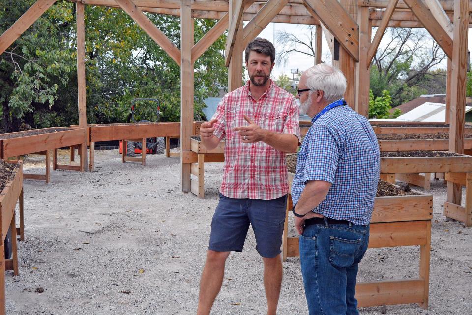 Columbia Center for Urban Agriculture co-founder Adam Saunders chats with Columbia's Ward 5 Council Member Don Waterman on Wednesday following the ribbon-cutting on the accessible Warriors Garden at the Mark and Carol Stevenson Veterans Urban Farm on Smith Street.