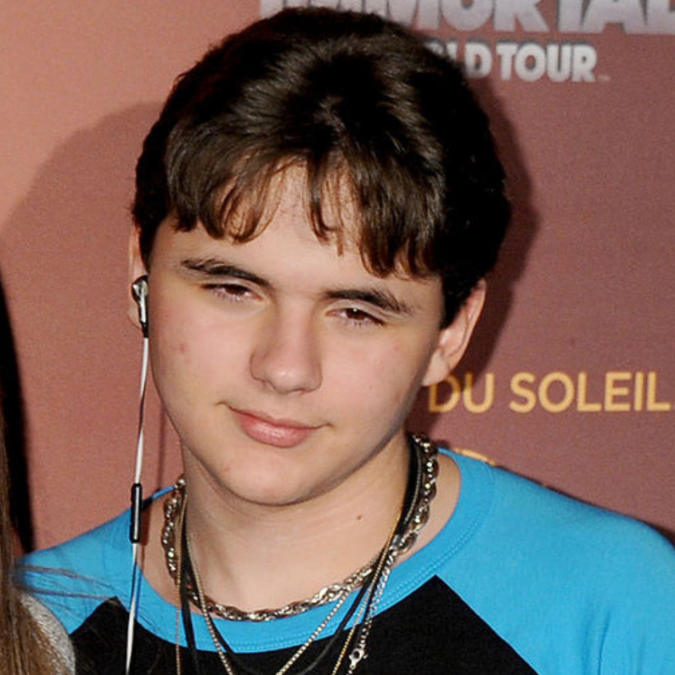 Person in blue top with headphones and necklace, squinting slightly, at an event