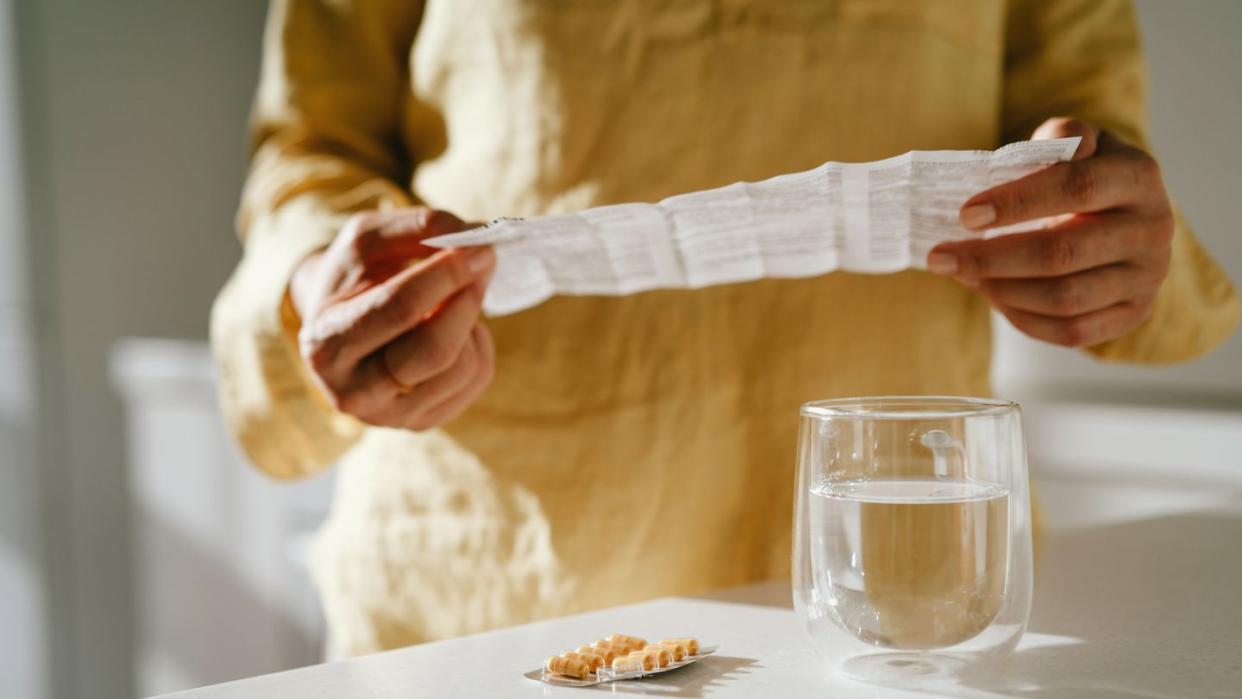 a woman standing at a table with green pills in her hand