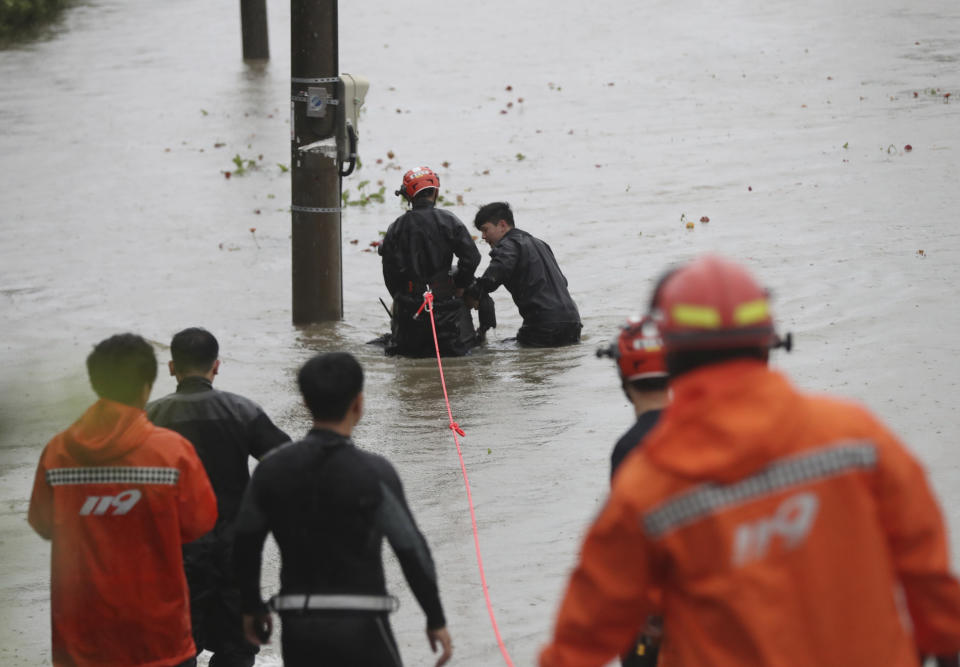 South Korean firefighters rescue a citizen near a river in Ulsan, South Korea, Tuesday, Sept. 6, 2022. Thousands of people were forced to evacuate in South Korea as Typhoon Hinnamnor made landfall in the country's southern regions on Tuesday, unleashing fierce rains and winds that destroyed trees and roads, and left more than 20,000 homes without power. (Kim Yong-tai/Yonhap via AP)