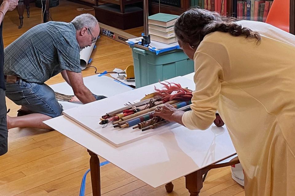 Leola One Feather, right, of the Oglala Sioux Tribe in South Dakota, lines up a grouping as John Willis photographs, left, Native American artifacts on July 19, 2022, at the Founders Museum in Barre, Massachusetts. The private museum, which is housed in the town library, is working to repatriate as many as 200 items believed to have been taken from Native Americans massacred by U.S. soldiers at Wounded Knee Creek in 1890. Willis is photographing the items for documentation, ahead of their expected return to the tribe. (AP Photo/Philip Marcelo)