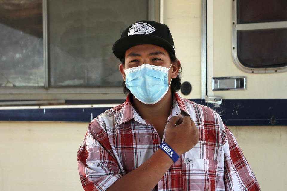 In this Oct. 19, 2020 photo, Cuba High School senior Cyliss Castillo shows off his slap bracelet USB drive loaded with assignments that was delivered by school bus driver Kelly Maeastas, outside Cuba, New Mexico. The closing of classrooms and the switch to remote learning because of the coronavirus outbreak have left Castillo and other students in this school district on the sparsely populated fringe of the Navajo Nation in New Mexico profoundly isolated, cut off from other people — and, in many cases, the grid — by sheer distance. (AP Photo/Cedar Attanasio)