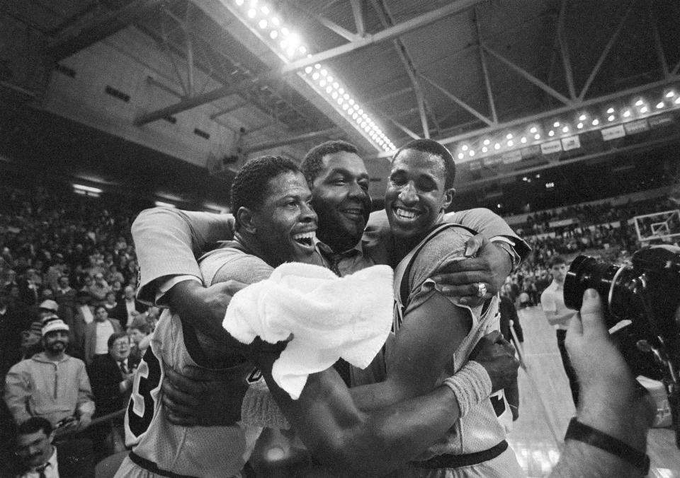 FILE - Georgetown University's Patrick Ewing, left, and teammate Ralph Dalton, right, get a hug from head coach John Thompson, center, after Georgetown downed Georgia Tech 60-54 during NCAA an NCAA college basketball game in Providence, R.I., March 24, 1985. (AP Photo/Paul Benoit, File)