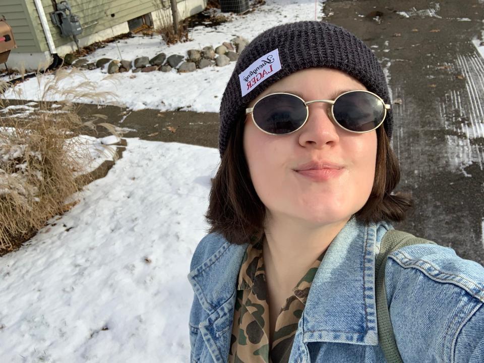 Gabi Stevenson in sunglasses and a hat standing in front of a snowy yard