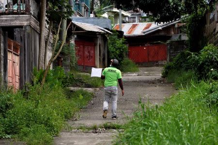 A member of a humanitarian volunteers team walks with a white flag as he searches for survivors or victims due to the fighting in the centre of Marawi City, Philippines June 25, 2017. REUTERS/Jorge Silva