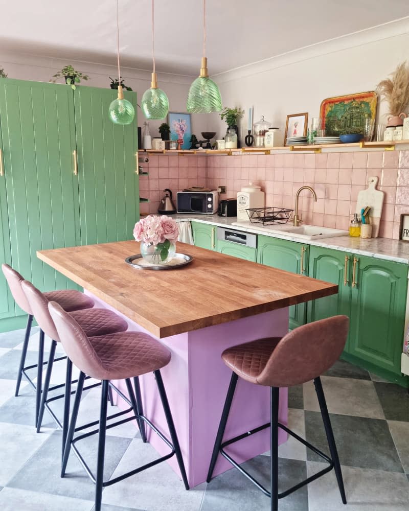 A pink painted kitchen island with butcher block countertops in a newly remodeled home.