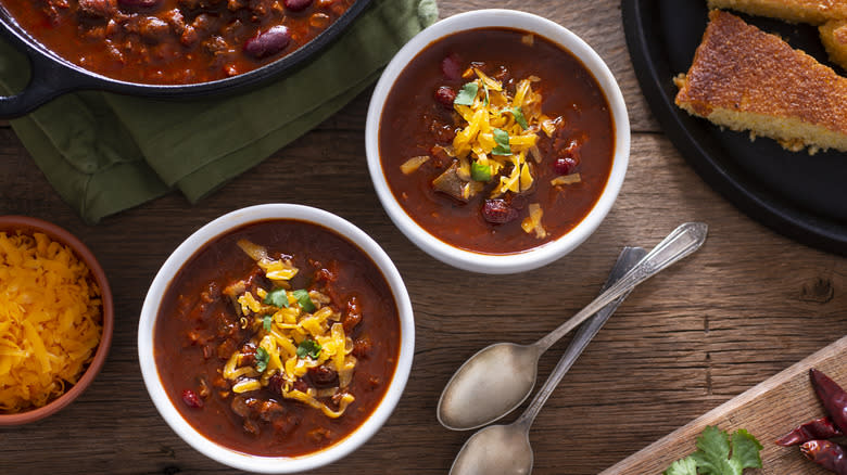 Bowls of chili next to cornbread