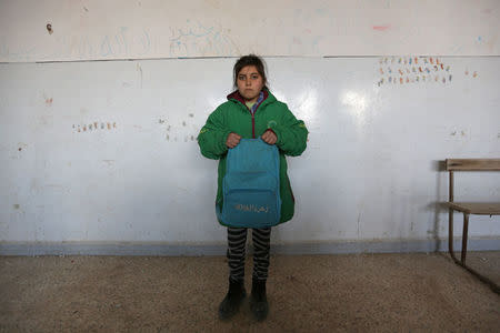 A student poses as she holds a Unicef-donated school bag in 'Aisha Mother of the BelieversÕ school which was recently reopened after rebels took control of al-Rai town from Islamic State militants, Syria January 17, 2017. Islamic State militants covered the UNICEF logo featured on the bag with the slogan "Flower of the Caliphate" when they were in control of al-Rai town. REUTERS/Khalil Ashawi