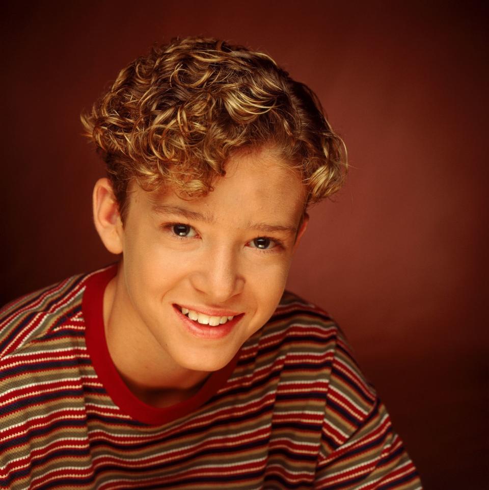 justin timberlake smiles at the camera, he wears a multicolored striped shirt