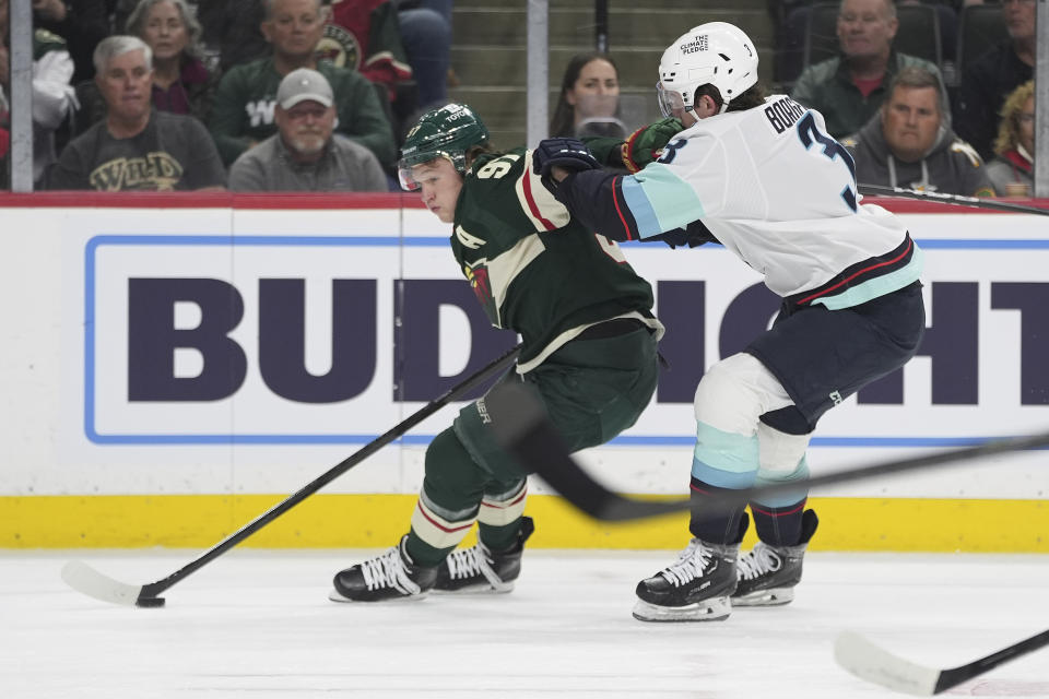 Minnesota Wild left wing Kirill Kaprizov, left, fends off Seattle Kraken defenseman Will Borgen during the first period of an NHL hockey game Thursday, April 18, 2024, in St. Paul, Minn. (AP Photo/Abbie Parr)