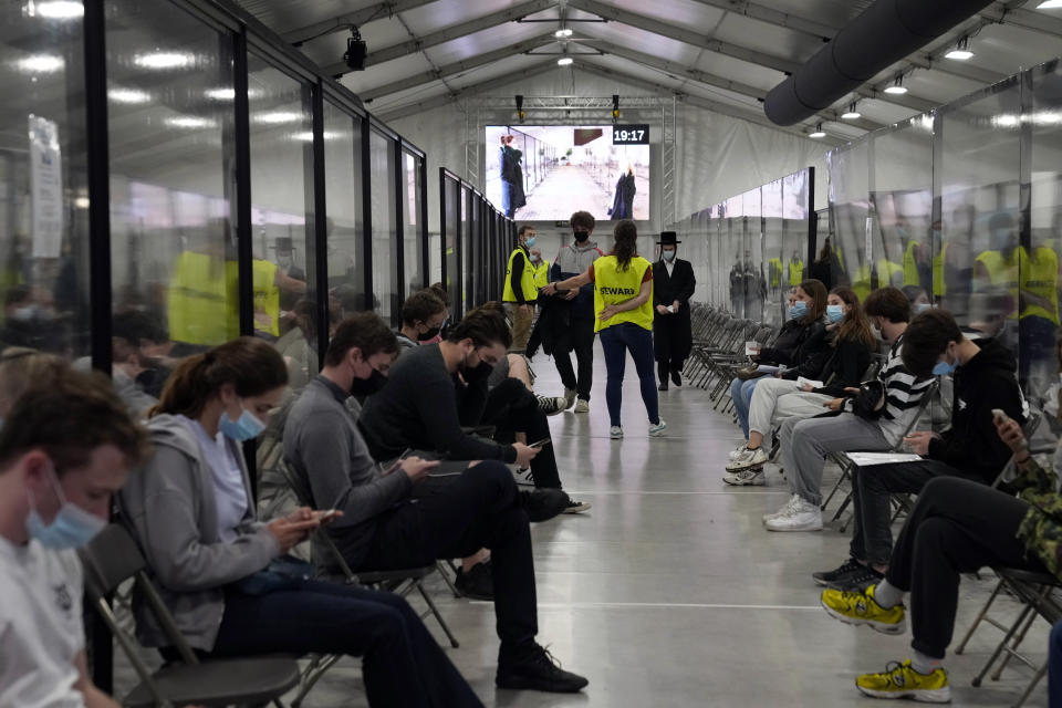 People sit in a waiting room after receiving their COVID-19 vaccine at the Vaccine Village in Antwerp, Belgium on Wednesday, June 30, 2021. (AP Photo/Virginia Mayo)